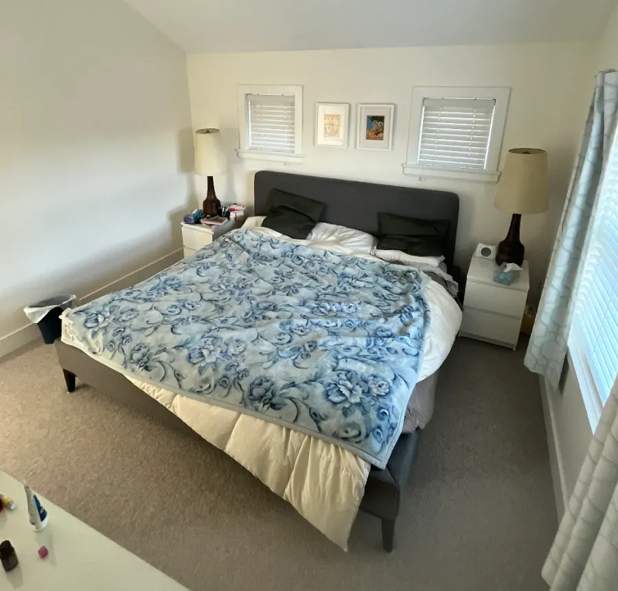 David's bedroom before: a floral throw over a rumpled duvet and cluttered nightstands